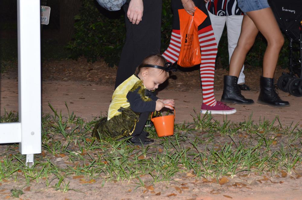 Young girl in yellow costume picking grass and putting it in orange pale